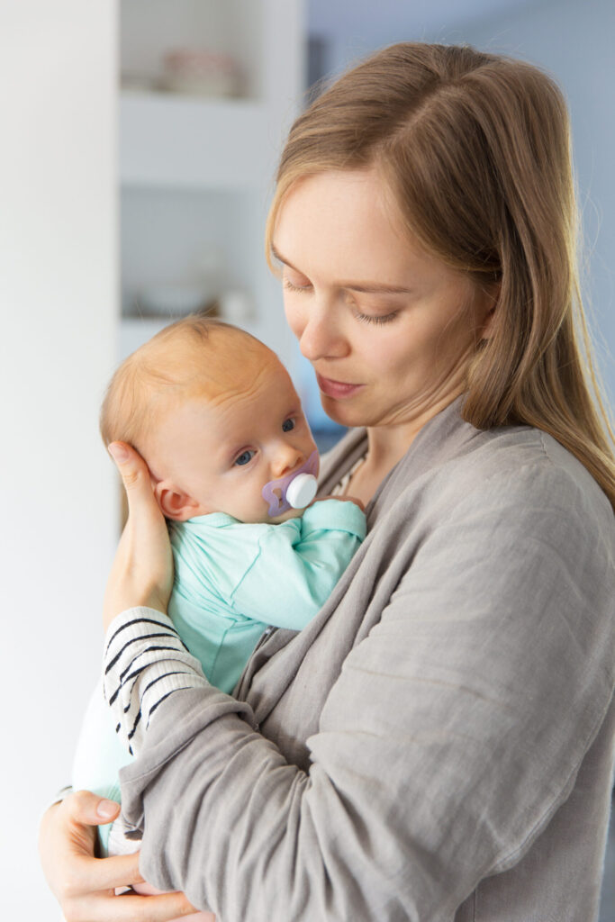 focused new mother cuddling baby with soother scaled.jpg